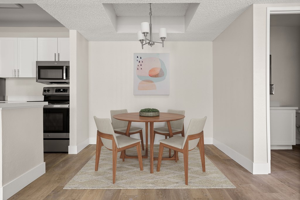 a dining room with a table and chairs and a kitchen in the background